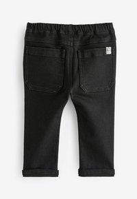 Pantalon en denim noir avec une texture douce, ceinture élastique et deux poches arrière. Les ourlets sont retroussés, avec une petite étiquette au dos.