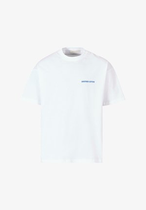 Weißes Baumwoll-T-Shirt mit Rundhalsausschnitt und kurzen Ärmeln, mit einem blauen Textlabel "ANOTHER COTTON" auf der linken Brustseite.