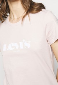 Ljusrosa Levi's t-shirt med vitt logo och texten "Sedan 1873". Korta ärmar, rund halsringning och mjukt bomullstextur.