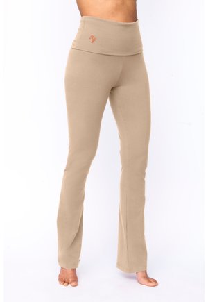 Beige Yogahosen mit einem breiten Bund und besticktem Logo. Hergestellt aus weichem, elastischem Stoff, haben sie eine figurbetonte Silhouette und ausgestellte Beine.