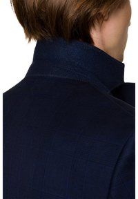 Granatowa marynarka w kratę z wysokim kołnierzem, z wełnianego materiału, z subtelnymi detalami szycia. Tekstura wydaje się gładka, z zarysowanym krojem.