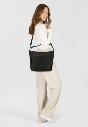Schwarze Schultertasche aus Leder mit strukturiertem Oberflächenmaterial, verstellbarem Trageriemen und silbernem Zubehör, auf einem hellgrauen Hintergrund präsentiert.