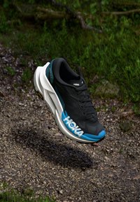 Black running shoe with blue accents and white midsole. Features a textured upper and branded logo on the side. Grooved outsole for traction.