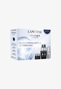 Ensemble de soins ultimes Lancôme Génifique dans une boîte blanche ; comprend trois flacons de sérum et un pot de crème avec des accents noirs et argentés.