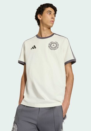 T-shirt crème avec des accents gris, doté d'un col rond et de manches courtes. Logo brodé avec un motif de laurier sur la poitrine.