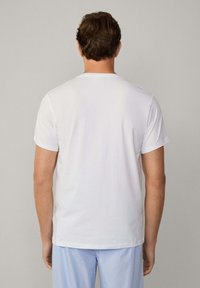 Camiseta de algodón blanca con cuello redondo y mangas cortas, vista desde la parte posterior. Textura suave y diseño ajustado, sin patrones ni acentos.