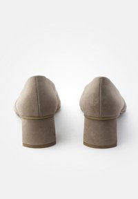 Escarpins en suède beige avec un talon bloc épais. Les talons sont effilés à l'avant avec une texture lisse et un minimum de détails.