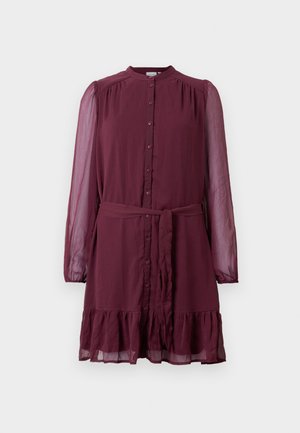 Burgundska obleka z dolgimi rokavi in gumbom spredaj, tkaninasti pas pri pasu, prozorne rokave in volanast rob na belem ozadju.