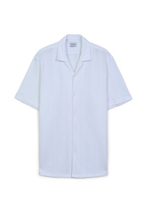 Camicetta bianca a maniche corte realizzata in un tessuto testurizzato, con colletto morbido e chiusura frontale con bottoni; vestibilità leggermente ampia, design semplice.