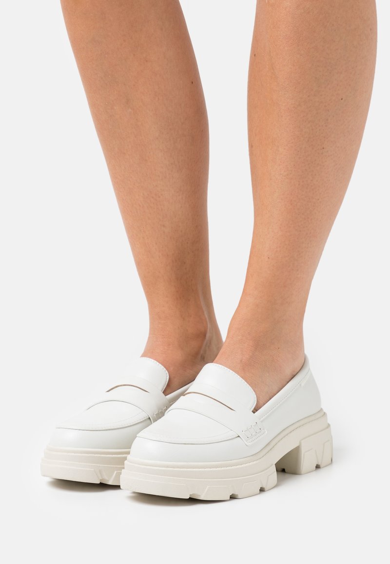 White loafers with a chunky platform, smooth texture, minimalist design, featuring a single decorative seam across the upper section.