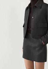 Gray herringbone wool blend jacket with a collared neckline and front pocket, paired with a matching gray mini skirt.