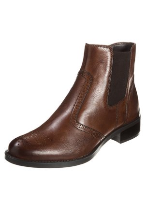 Brun læder Chelsea-støvle med brogue-detaljer, sort elastisk sidestykke og lav sort hæl.