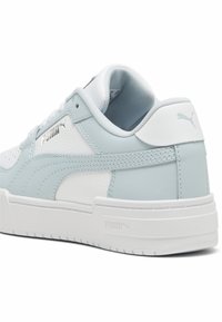 Les baskets PUMA présentent un dessus en cuir bleu clair et blanc, un motif texturé, un col rembourré et une semelle en caoutchouc blanche avec des détails de logo.