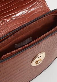 Borsa in pelle marrone a effetto coccodrillo con chiusura a girello dorata e tasca interna con cerniera etichettata "Pieces".