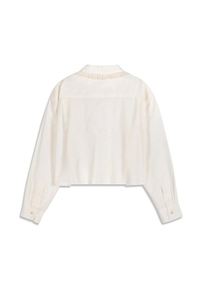 Blouse crème à manches longues avec poignets boutonnés et délicate dentelle le long de l'encolure arrière, vue de dos.