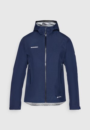 Marineblaue, wasserdichte Kapuzenjacke mit durchgehendem Frontreißverschluss, zwei seitlichen Reißverschlusstaschen, Mammut-Logo auf der Brust und Gore-Tex-Logo nahe dem Saum.