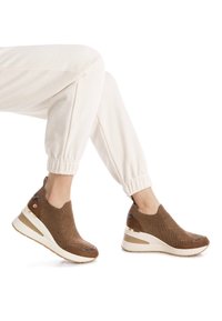 Zapatillas de punto marrones con una parte superior texturizada, tacón de cuña y acentos en crema. Presenta una lengüeta y detalles metálicos en el talón.