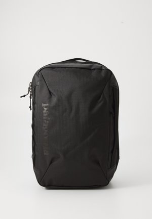Black backpack with a textured fabric, featuring a zippered closure, side pockets, and a logo printed on the front. Compact and rectangular design.