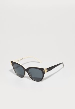 Cat-Eye-Sonnenbrille mit schwarzen Rahmen und grauen Gläsern. Mit beigen Bügelspitzen und goldenen Akzenten auf der Vorderseite.