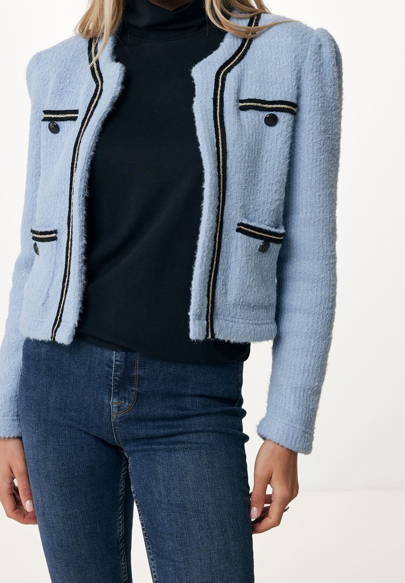 Veste en tweed bleu clair avec des accents rayés noirs et dorés, dotée de deux poches avant et d'une finition texturée. Design ajusté et court.