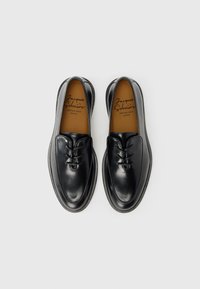 Sorte lædersko med rundet tå, snørelukning og glat finish. Indeholder indersåler i tanfarvet læder. Enkel, klassisk form.