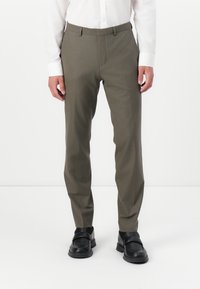 Olive green trousers with a tailored fit, belt loops, and a smooth fabric texture, paired with black loafers and a white shirt.