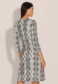 Schwarz-weißer Schlangenprint-Kleid mit ¾-Ärmeln, tailliertem Design und ausgestellt geschnittenem Saum. Glatte Textur und gemustertes Material. Einfache runde Ausschnitt.