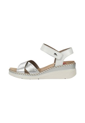 Sandalia cuña blanca y plateada con tiras delanteras cruzadas, correa en el tobillo con cierre de velcro y detalle de costura en la suela.