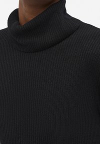 Schwarzer gerippter Rollkragenpullover aus weichem, strukturiertem Strick. Mit hohem Kragen und tailliertem Design für eine enganliegende Optik.