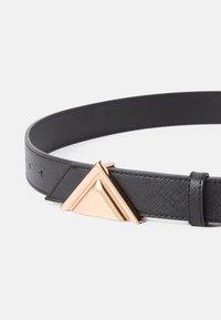 Cinturón de cuero negro con una superficie texturizada, con una hebilla de metal en tono dorado en forma triangular como punto focal principal.