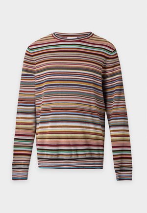 Homme portant une chemise à manches longues rayée horizontale multicolore et un short assorti à rayures verticales, chaussettes bleu marine et baskets blanches, debout.