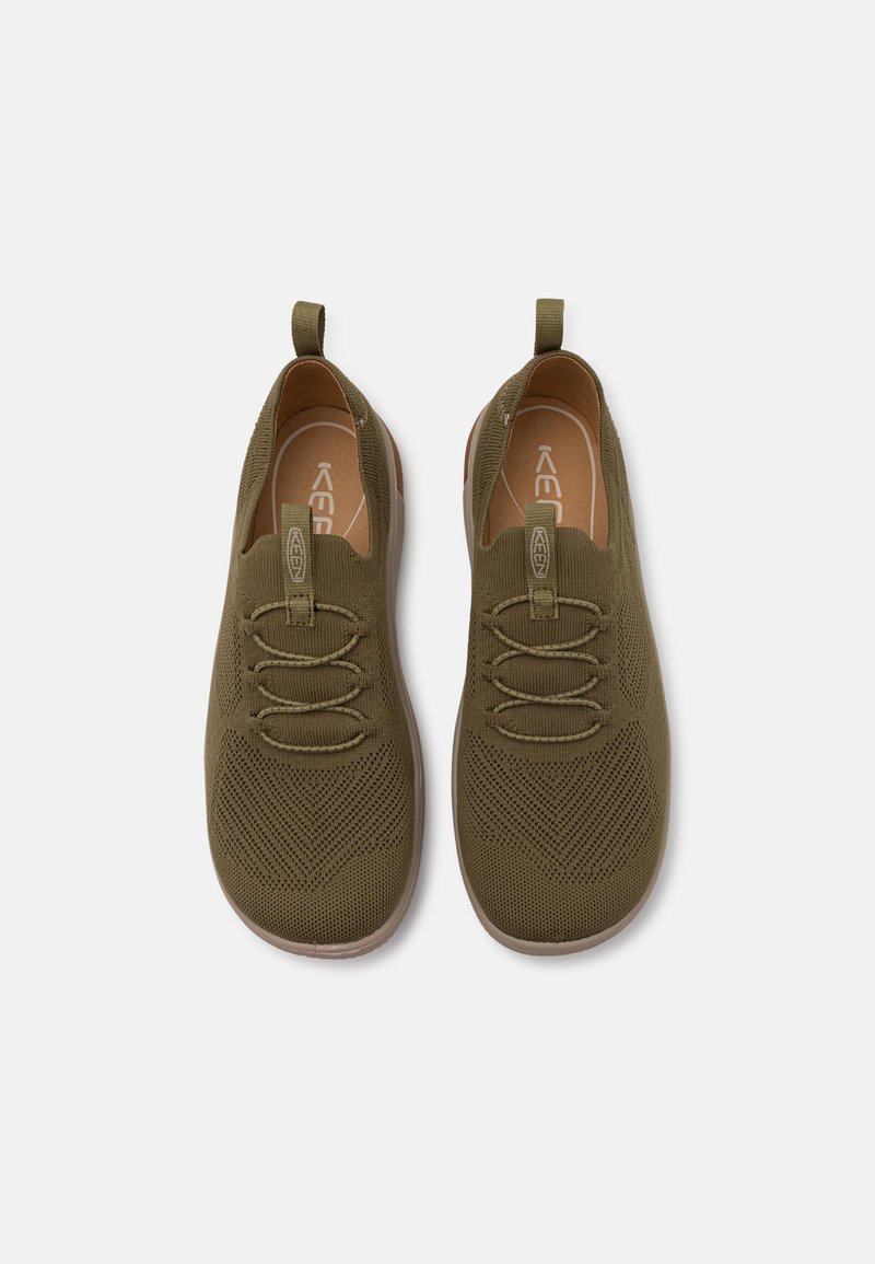 Oliwkowe buty typu slip-on z teksturowanym, dzianinowym wierzchem, elastycznymi sznurowadłami i pętelkami do zakupu; mają jasnobrązową podeszwę.
