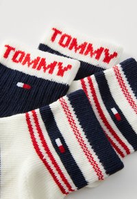 Gestreifte Socken in Marineblau, Weiß und Rot, mit der Marke "TOMMY" in Rot auf dem Bund und einem kleinen Logo-Detail auf dem Sockenkörper.