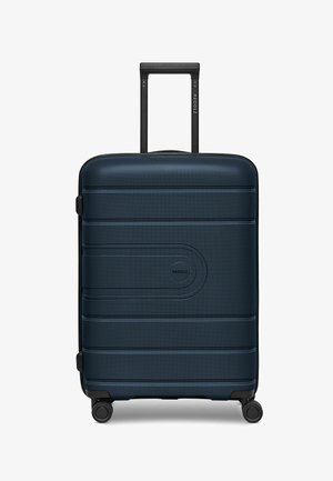 Valigia rigida blu navy con strisce orizzontali in rilievo, manico telescopico nero e quattro ruote nere per la mobilità. Logo sulla parte anteriore.