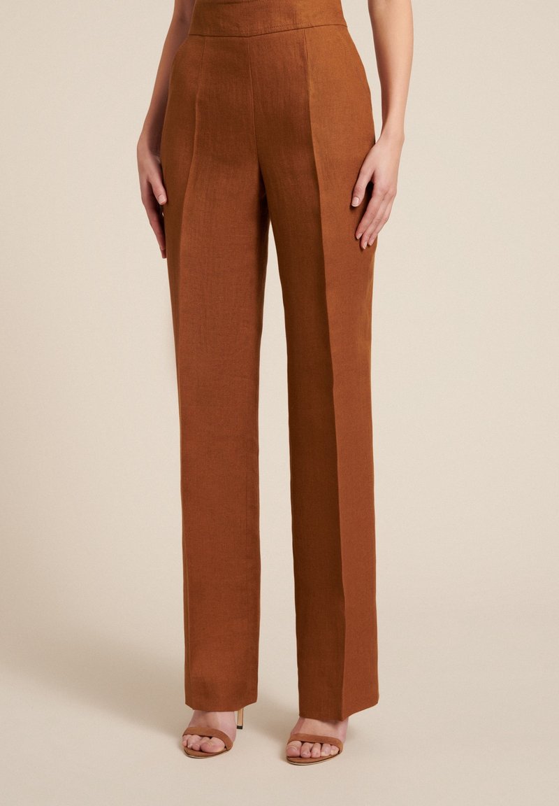 Pantalon en lin marron taille haute avec une coupe ajustée, présentant des plis avant nets et un design droit. Texture lisse sans motifs visibles.