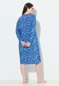 Abito a maniche lunghe in tessuto blu con motivo floreale. Presenta un collo rotondo e spacco laterale, che arriva a metà polpaccio. Tessuto morbido.