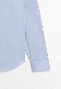 Light blue shirt with vertical stripes, featuring a long sleeve, round hem, and buttoned cuff detail, made of a smooth fabric.