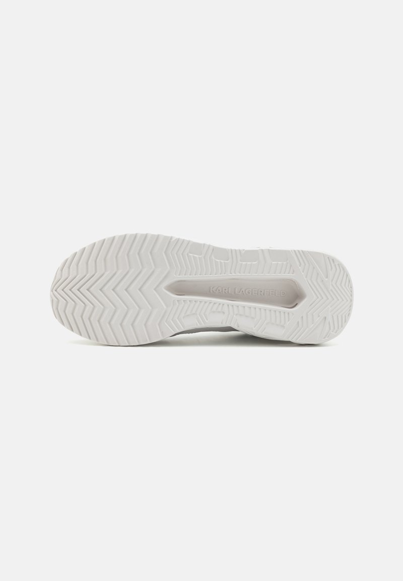 Suela de zapatilla blanca con una superficie de goma texturizada, que presenta un patrón en espiga y una marca en relieve. Diseño limpio y minimalista.