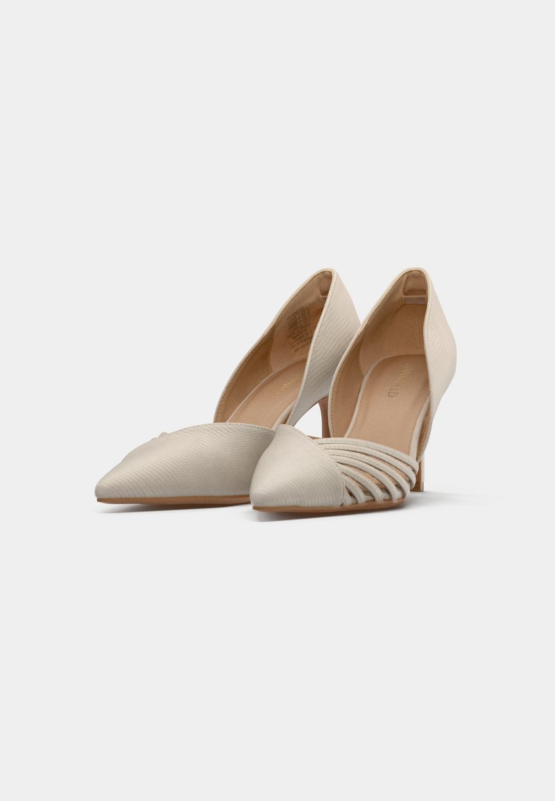 Zapatos de tacón alto beige con punta afilada, parte superior texturizada y detalle con ranuras a lo largo del mediopié, con un tacón delgado.