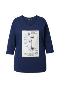 T-shirt in cotone blu navy con scollatura a V, maniche 3/4 e una stampa grafica floreale che presenta fiori rosa e blu su uno sfondo chiaro.
