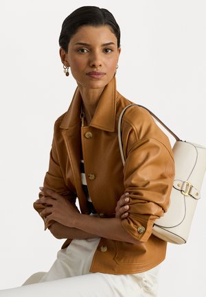 Καφέ ψεύτικο δερμάτινο μπουφάν με γιακά και χρυσά κουμπιά, συνδυασμένο με μια άσπρη τσάντα χειρός που διαθέτει χρυσή λεπτομέρεια και λείο φινίρισμα.