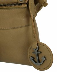 Borsa in pelle marrone con finitura testurizzata, dotata di chiusura a zip e un'etichetta circolare con un accento di ancora metallica.