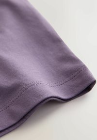 Fliederfarbenes T-Shirt mit glattem Stoff und dezenter Nahtdetail. Der Stoff ist leichtes Baumwollmaterial mit leicht umgeschlagenem Saum.