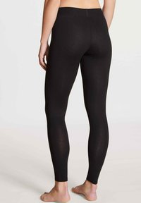 Zwarte legging gemaakt van rekbare stof met een gladde textuur, hoge tailleband en een strakke pasvorm die tot aan de enkel reikt.