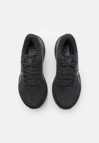 Svarta sportskor med en texturerad mesh-övre del, rund tå och grå accenter på sidorna. Snören är trädda genom öglorna för en säker passform.