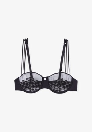 Czarny stanik z przezroczystymi miseczkami z siateczki i dekoracyjnymi czarnymi akcentami. Posiada wiele cienkich ramiączek oraz usztywnioną konstrukcję z fiszbiną.