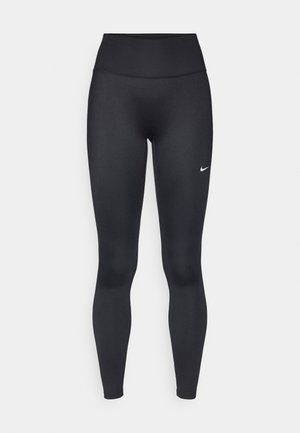 Colanți sport negri, talie înaltă, dintr-un material elastic. Au o textură netedă și un mic logo alb Nike pe coapsa stângă.