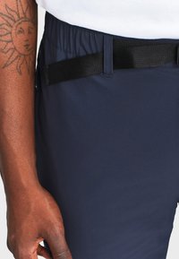 Navy broek met een elastische tailleband en een zwarte webbingriem. Gladde stof met een minimalistisch ontwerp, zonder zichtbare zakken.