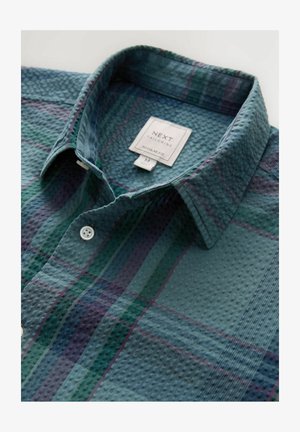 Lühikese varrukaga roheline ruuduline särk, millel on tekstuuriga kangas, valged nööbid ja kraega kaelus. Sildil on kirjas "NEXT, Regular Fit, M."