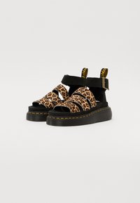 Leopardprint platform sandaler med sorte ruskindsremme og metalliske detaljer. Har justerbar ankelrem og gul syning på sålen.